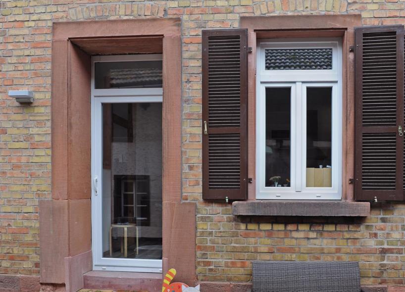 Holzfenster mit Klappläden und Holzhaustür in weiß 